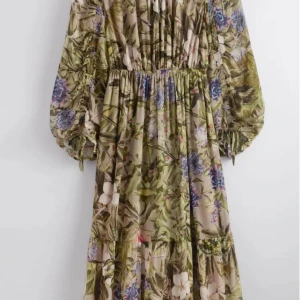 Blommig långklänning från & Other Stories - Superfin långklänning från & Other Stories med blommigt mönster i grönt, beige, lila och blått. Klänningen har långa puffärmar, markerad midja och volangdetaljer. Perfekt för dig som gillar romantiska vibes och flowy material.