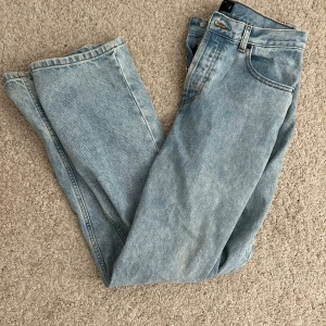  jeans straight fit -  jeans i ljusblå tvätt med raka ben och knappgylf. Jeansen har fem fickor och är tillverkade i robust denim. Perfekta för en avslappnad och tidlös stil.