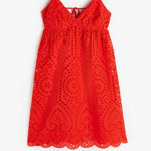 Röd broderad kortklänning med snörning - Superfin röd kortklänning med broderade detaljer och tunna axelband. Klänningen har v-ringning, öppen rygg med snörning och ett vackert hålmönster i tyget. Perfekt för varma dagar och sommarens alla tillfällen.