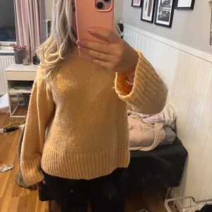 Orange stickad tröja med vida ärmar - Supermysig orange stickad tröja med breda, ribbade muddar och avslappnad passform. Tröjan har rund halsringning och långa ärmar som ger en chill vibe. Perfekt för lager-på-lager och att mysa runt i under kyliga dagar.