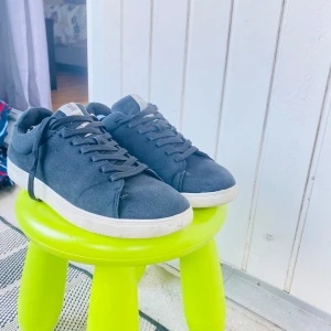 Svarta sneakers med vit sula - Stilrena svarta sneakers med vit platt sula och klassisk snörning. Skorna har en enkel och clean design som passar till det mesta. Ovandelen är i textil och de har rund tå för en avslappnad look.