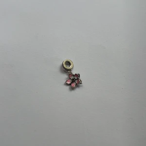 Pandora charm -   "Hey there! 👋 Check out this stunning silver charm with a pink and silver flower design. It's got a delicate charm loop at the top and a striking black center. It's perfect for adding a touch of elegance to any bracelet  