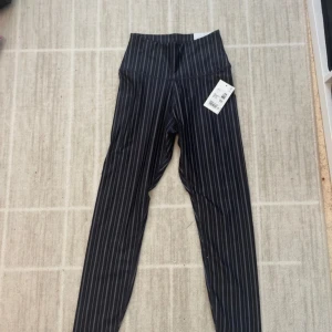 Svarta randiga träningsbyxor. - Snygga svarta träningsbyxor med vita ränder. Stretchigt material som sitter tajt och ger en clean look. Perfekta till träning eller andra idrotter.