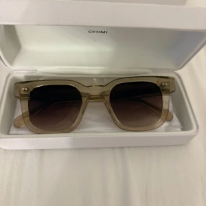 Beige solglasögon CHIMI Ecru - Snygga solglasögon från CHIMI i modellen Ecru. Rektangulära bågar i transparent beige plast med bruna tonade glas. Kommer med originalfodral. Perfekta för dig som vill ha en clean och modern look. Använda max 1 gång❤️⚠️Om ni tycker på köp direkt får ni gärna använda postnord för min instabox funkar ej!⚠️Kan gå ner i pris vid snabb affär 