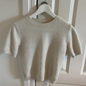 Stickad T-shirt HM xs - En stickad T-shirt från HM i storlek xs. Den är anvönd några gånger men kvaliten är väldigt bra.🥰färgen skulle jag säga är krämvit, den är lite mellan vit och beige