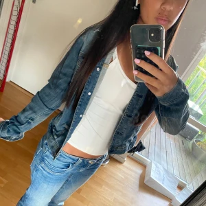 Klassisk blå jeansjacka i storlek 36 - Snygg blå jeansjacka från Authentic & Original i klassisk modell med två bröstfickor och knappar framtill. Jackan har en normal passform och är tillverkad i slitstarkt denimtyg. Perfekt att slänga över en hoodie eller t-shirt för en cool look.