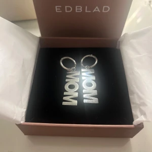 Silverörhängen ”MOM” från Edblad - Fina örhängen från Edblad i silverfärgat material med texten 'MOM”. Jätte fint skick,aldrig använda! Ny pris 400 kr 🩶