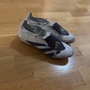 Adidas Orlando City fotbollsskor - Unika vita och lila Adidas fotbollsskor med Orlando City-logga och guldiga detaljer. Skorna har snörning och är tillverkade i syntetmaterial. Sidorna pryds av texten 'FOREVER A LION' och 'KAKA'. Perfekta för dig som vill sticka ut på planen. KAKA X ADIDAS PREDATORS COLLAB. Skorna är lite använda men funkar som nytt! 