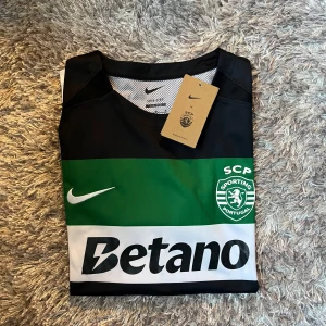 Helt ny! Sporting CP Gyökeres matchtröja Nike - Helt ny! Sporting CP:s officiella matchtröja med Gyökeres och nummer 9 på ryggen. Tröjan är kortärmad, har breda svarta, gröna och vita ränder, klubbmärke och Nike-logga på bröstet samt Betano-sponsor. Tillverkad i lätt och ventilerande polyester.