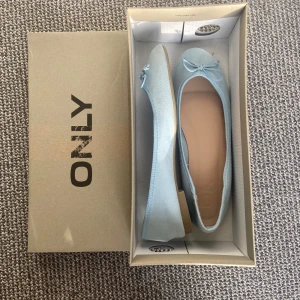 Ljusblå ballerinaskor med rosett från ONLY - Säljer ett par ljusblå ballerinaskor från ONLY med söt rosettdetalj framtill. Skorna har rund tå och platt sula, perfekta för en stilren och enkel look. Säljer eftersom de inte kommer till användning🩵🩵