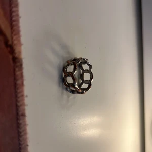 Silverfärgad ring med kedjemönster - Cool ring i silverfärg med öppet kedjemönster runt hela bandet. Perfekt accessoar för dig som gillar en edgy och trendig stil. Ringen har en unik design som sticker ut och passar till många olika outfits.