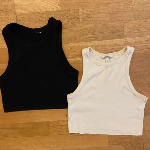 2-pack ribbade croppade linnetoppar - Säljer två croppade linnetoppar från H&M, en i svart och en i vit. Båda är ribbade och ärmlösa med hög halsringning och tight passform.                                                                                                      Bra skick-men den vita toppen har en liten liten fläck som syns knappt på både bilden och i livet. 