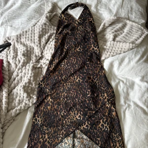 Klänning i leopardmönster - Så cool och unik klänning i leopardmönster! Klänningen har knytning runt halsen och en öppen rygg. Kommer aldrig till användning! 🩷vet ej storlek men skulle gissa på ca S/M/36