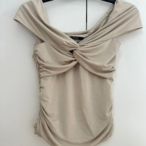 Snygg beige topp -  Säljer denna snygga beiga toppen med knyta längst fram. Den är helt nytt skick och aldrig använd, prislappen sitter kvar. Hör av er vid frågor om pris eller annat!💖liten smink fläck på framsidan (syns på bild 1) men i och med allt lappen finns kvar så är den inte använd.