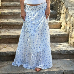 Vit långkjol med blå blommor - Superfin långkjol i vitt med små blå blommor och bred resår i midjan. Sparsamt använd, mycket bra kvalitet💘😍storleken är XS/S enligt hemsidan!