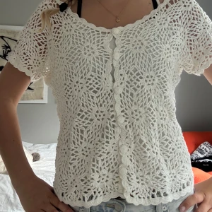 Vit virkad blus med blommönster - Superfin vit virkad blus med kort ärm och blommigt mönster. Koftan har knappar framtill 