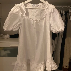 Vit volangklänning med puffärm - Supersöt vit klänning med puffärmar, volangdetaljer vid ärmslut och nederkant samt spets runt halsringningen. Pris kan diskuteras. Storlek S/M