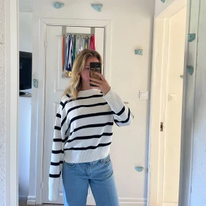Vit och svart randig stickad tröja - Säljer en vit stickad tröja med svarta horisontella ränder. Tröjan har lång ärm, rund halsringning och en avslappnad passform. Perfekt till jeans för en enkel och stilren look. Storlek L men passar som S/M.
