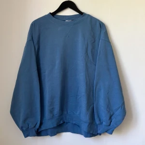Blå sweatshirt från H&M Divided - Säljer en blå oversized sweatshirt från H&M Divided. Tröjan har rund halsringning, långa ärmar och ribbade muddar vid ärmslut och nederkant. Perfekt för en avslappnad stil och enkel att matcha med jeans eller leggings.