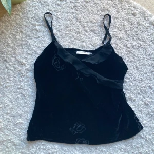 Vintage linne sammet - Fin topp med smala axelband och en dekorativ volangdetalj vid halsen. Från gamla Hennes collection. Sammetstyg. Mönster av rosor. Storlek 38 men liten i storleken så passar 36. Croppad längd, går till över naveln. 80% viskos och 20% siden.