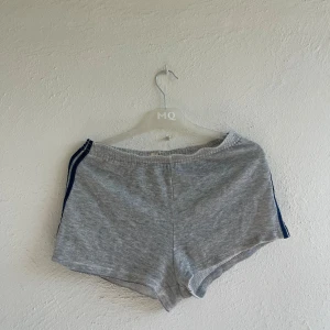 Mjukisshorts - Gråa shorts med blå ränder längs sidorna. Mjukt bomullsmaterial och en bakficka. Väl använda men fortfarande i bra skick!✨