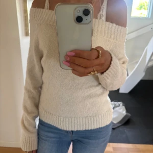 Offshoulder stickad tröja i beige - Säljer en superfin offshoulder stickad tröja i beige. Tröjan har bred ribbad kant upptill och vid ärmslut samt nederkant. Perfekt att styla med jeans för en avslappnad men snygg look.