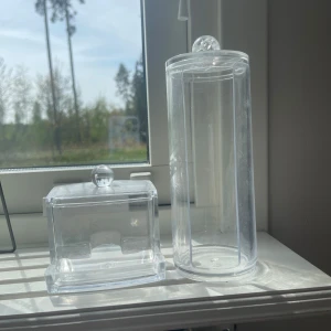 Genomskinliga tops och pads förvaring - Två genomskinliga sminkförvaringsburkar i plast, en rund och hög med lock och en fyrkantig med lock. Perfekta för att förvara pads och tops i. Stilren och enkel design som passar på sminkbordet. 50kr styck