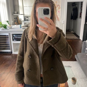Khaki jacka - Säljer en olivgrön jacka från H&M i ullblandning med dubbelknäppning framtill. Jackan har bred krage, långa ärmar och en boxig, lite oversized passform. Perfekt för höst och vår. Snygg att styla med jeans eller kjol.