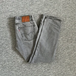 Gråa Levi's 501 jeans - Säljer ett par klassiska gråa Levi's 501 jeans med raka ben och femficksmodell. Jeansen har normal passform, knappgylf och den ikoniska läderpatchen bak i midjan. Hör av dig vid frågor 🤩