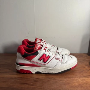 New Balance 550  - Säljer ett schyssta New Balance 550 sneakers i vitt med röda och svarta detaljer. Skorna är i väldigt bra skick och passar perfekt nu till sommaren och varmare väder.