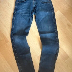Blå Replay jeansbyxor herr w32 l32 - Säljer ett par klassiska blå jeans från Replay, modell M914Y. Byxorna har raka ben, fem fickor och normal passform. Snygga kontrastsömmar och läderpatch bak i midjan. Perfekta till vardags för en stilren look.