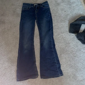 Blå bootcut jeans från Lindex - Snygga blå jeans från Lindex med bootcut passform och markerade sömmar. Klassisk femficksmodell med dragkedja och knapp framtill samt dekorativa sömmar på bakfickorna. köpte för 450kr och har ungefär haft den i kanske ett år💞storlek 152,