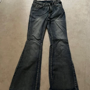 Blå bootcut jeans - Ett par blå bootcut jeans med klassisk femficksdesign och dragkedja. Jeansen har utsvängda ben, normal passform upptill och mid/hög midja. Perfekta för dig som gillar retrostil och vill ha ett par bekväma jeans med snygg siluett.