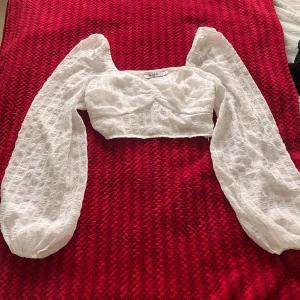 Vit croppad blus med puffärmar - Säljer en vit croppad blus med långa puffärmar och strukturmönster i tyget. Toppen har en söt och romantisk känsla med fyrkantig ringning och lätt volym i ärmarna. Perfekt för vår och sommar! 💕