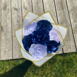 Bukett med konstgjorda rosor i blått och vitt - Säljer en snygg bukett med konstgjorda rosor i mörkblått och vitt. Blommorna är gjorda av glansigt tyg och är omsorgsfullt arrangerade i ett vitt papper med guldkant. Perfekt som dekoration eller present.