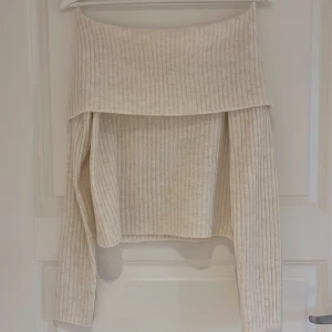 Beige ribbad offshouldertröja från Kappahl - Säljer en beige ribbad offshouldertröja från Kappahl. Tröjan har långa ärmar och en bred, nedvikt kant upptill som ger en snygg offshoulder-look. Perfekt för dig som gillar trendiga och stilrena plagg.