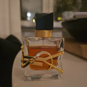 Yves Saint Laurent Libre Intense Eau de Parfum 30ml - Intense versionen! Ord. Pris 1100kr. Ca 20-22ml är kvar i flaskan vilket blir ett värde på ca 740kr. En lyxig parfym från Yves Saint Laurent med en elegant, fyrkantig glasflaska och guldiga detaljer. Flaskan har en svart asymmetrisk kork och innehållet är bärnstensfärgat. Doften är känd för sin fräscha och blommiga karaktär.