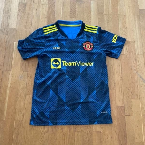 Manchester United tröja - Säljer en Manchester United bortatröja från Adidas. klubbmärke på bröstet, sponsortryck och Ronaldo 7 på ryggen. Perfekt för man united fans! Den är i bra skick förutom att trycket börjar bli lite slitet på vissa ställen