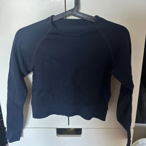 Mörkblå croppad ribbad tröja - Säljer en mörkblå croppad tröja med lång ärm och rund halsringning. Tröjan är ribbad och har en tight passform. 