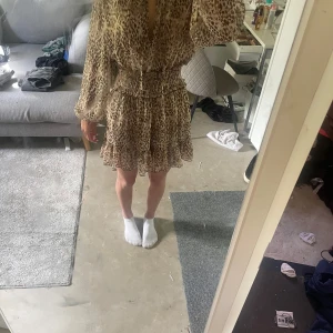 kortklänning från Zara - Säljer en snygg leopardmönstrad kortklänning från Zara med långa ärmar och smock i midjan. Klänningen har v-ringning med knyt framtill och volangdetaljer nertill. Perfekt för dig som vill sticka ut med ett djurmönster! Pris går såklart att diskutera de är bara att skriva🥰🥰