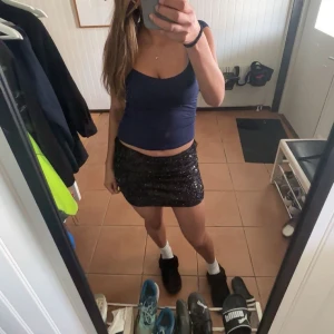 Svart glittrig kort kjol  - Säljer en svart kort kjol med glittriga paljetter. Kjolen har en tight passform och är perfekt för dig som vill sticka ut. Enkel att matcha med olika toppar pch perfekt inför sommaren. Storlek M men skulle säga att den är mer som S.