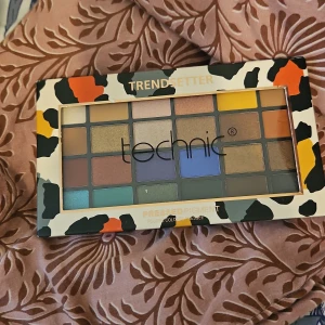 Ögonskuggspalett från Technic - Färgglad ögonskuggspalett från Technic med 24 olika nyanser. Paletten har en mix av matta och skimrande färger, perfekt för att skapa både vardagliga och festliga looks. Förpackningen har ett trendigt leopardmönster i svart, orange och beige.