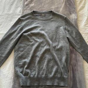 Grå tröja från Nordic Design Lab - Säljer en stilren grå tröja från Nordic Design Lab i mjuk merinoull. Tröjan har en klassisk rund hals och långa ärmar, perfekt för kyligare dagar. Den är enkel att matcha med olika outfits och ger en tidlös look.