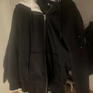 Moose Knuckles classic Bunny - Säljer en svart jacka från Moose Knuckles med dragkedja och mysigt foder. Jackan har en huva med vit fuskpäls och praktiska fickor. Perfekt för kyliga dagar. Nypris runt 5500kr i nk där denhär köptes. Priset går att diskutera