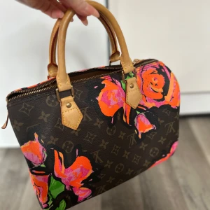 Stephen Sprouse Speedy 30  - Snygg handväska med ett klassiskt monogrammönster och färgglada blommor i rosa, orange och grönt. Väskan har bruna handtag och en dragkedja upptill. Perfekt för att ge en färgklick till din outfit! Handväskan från 2008 Äkta! 