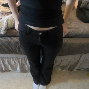 Svarta jeansbyxor - Snygga svarta jeansbyxor med normal passform och klassisk femficksdesign. Byxorna har en knapp och dragkedja framtill. Perfekta för en stilren look.