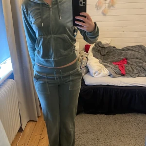 Mjukis byxor och kofta från juicy couture i grön - Säljer ett par gröna mjukisbyxor och kofta från juicy couture, koftan har luva och byxorna har fickor. Säljer pågrund av att det inte används, byxorna är i storlek XS och koftan är i M men ser mindre ut. Användt sparsamt så det är i bra skick. Byxorna och koftan tillsammans kostar 2500 i butik