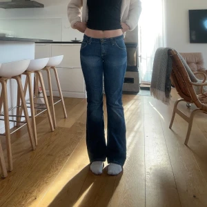 Blå bootcut jeans från Lee - Snygga blå bootcut jeans från Lee med låg midja. Perfekta för en avslappnad stil. Klassisk femficksdesign och knappgylf.