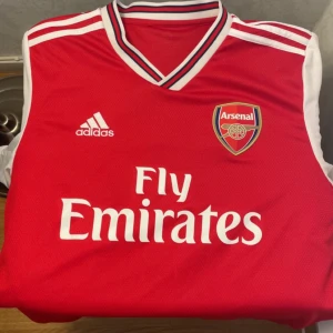 Arsenal fotbollströja  - Säljer en röd Arsenal fotbollströja från Adidas med vita detaljer och klubbens emblem på bröstet. Mycket bra skick och i storlek M