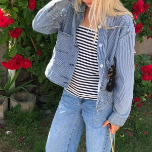 Blå- och vitrandig jeansjacka - Snygg blå- och vitrandig jeansjacka med knappar framtill. perfekt för vår och sommar. Den har långa ärmar och två framfickor samt skjortkrage